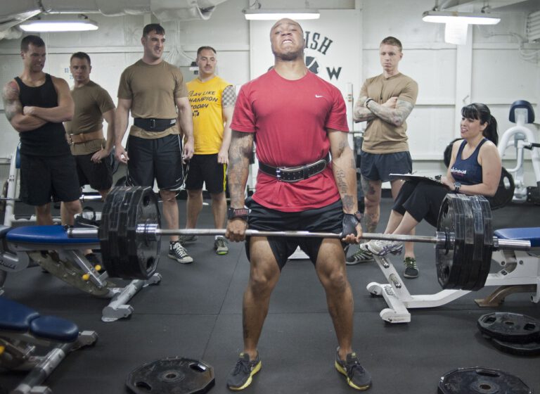Mann-hebt-gewichte-mit-einer-Gruppe-sportler-im-Fitnesstudio